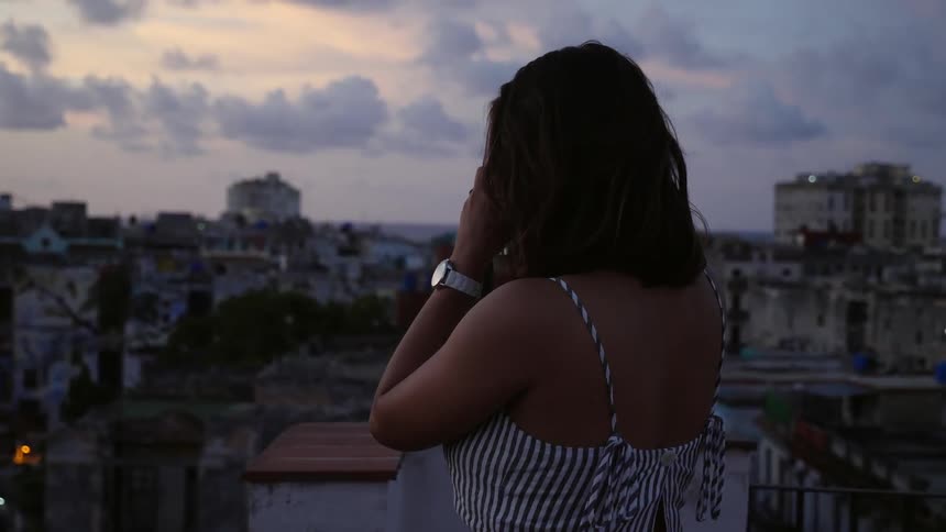 A woman takes a photo from a rooftop