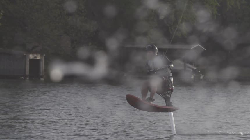 A man is water skiing sitting on a board