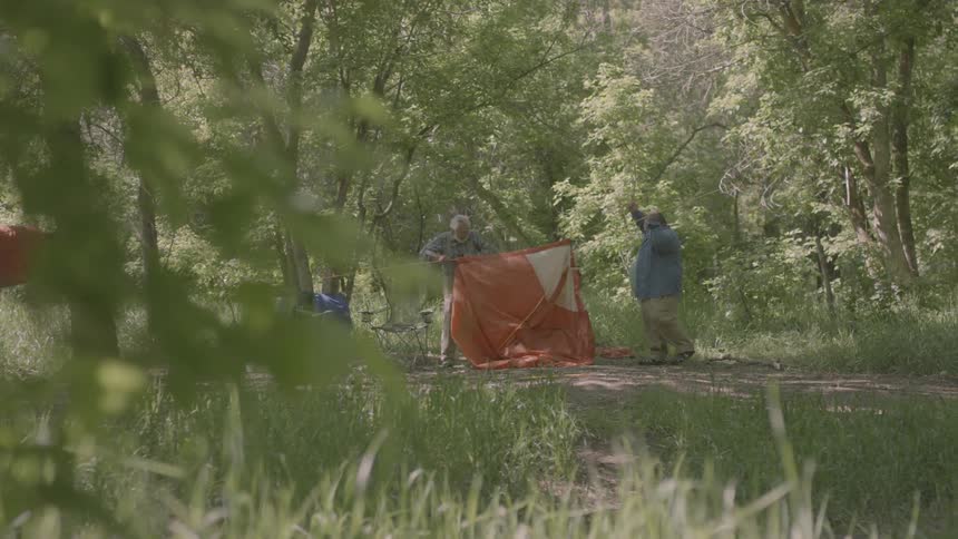 Two people set up a tent at a campground