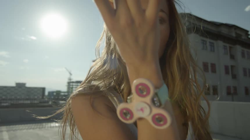 A woman models on a rooftop with fidget spinners
