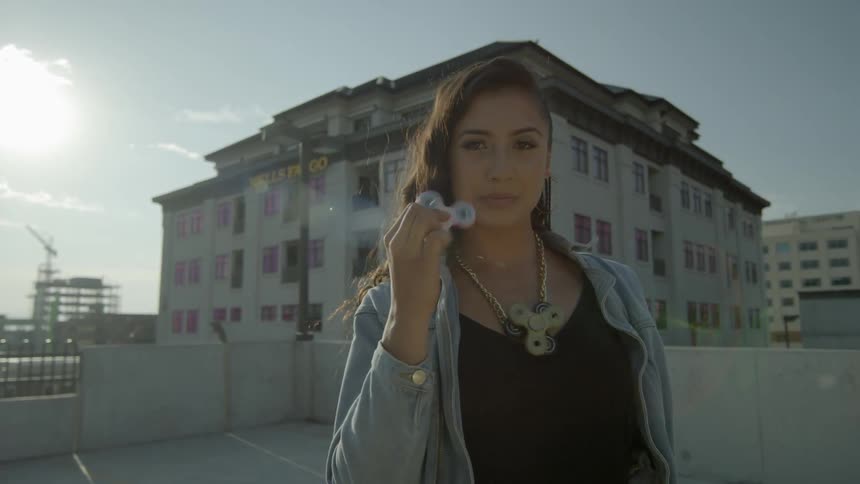 A woman models with rotating fidget spinners on a rooftop