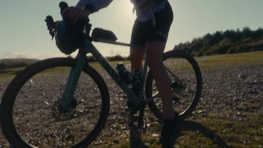 Teenage girl gets on her bicycle in a rural field