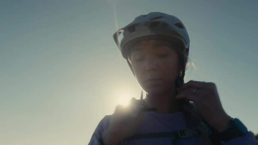 Cyclist putting on helmet in sunlight