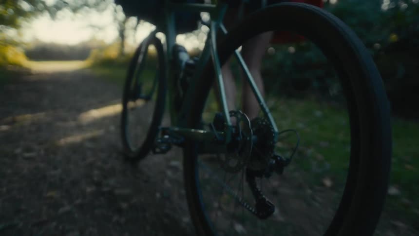 Bicycle pedal moving along a dirt trail under natural light