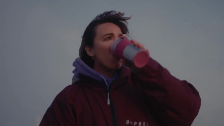 Woman drinks from a thermal mug outdoors during dawn or dusk