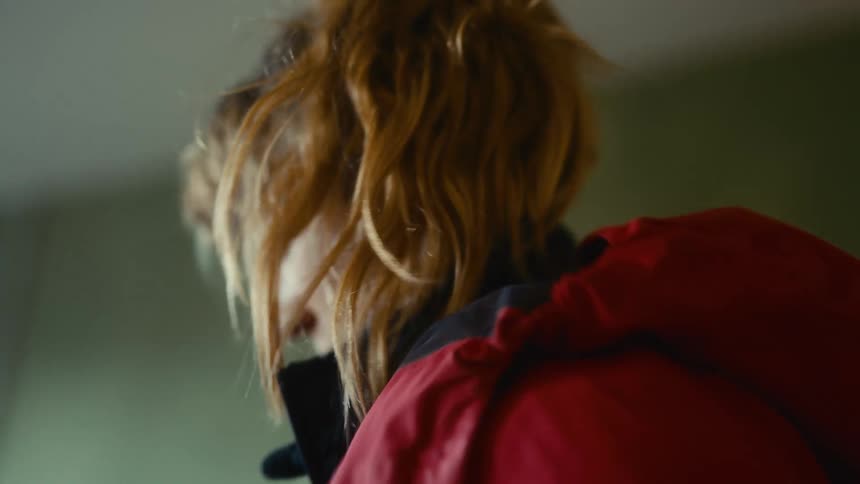 Woman puts on her coat while standing indoors