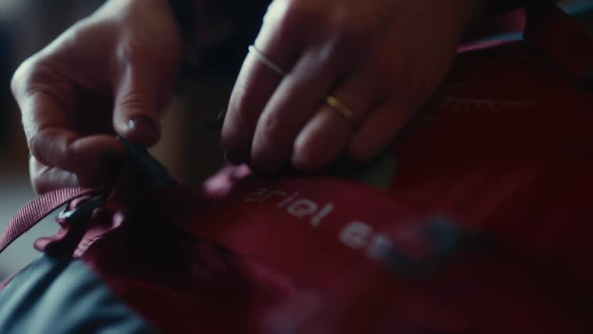 Female hands fastening straps on a red backpack indoors