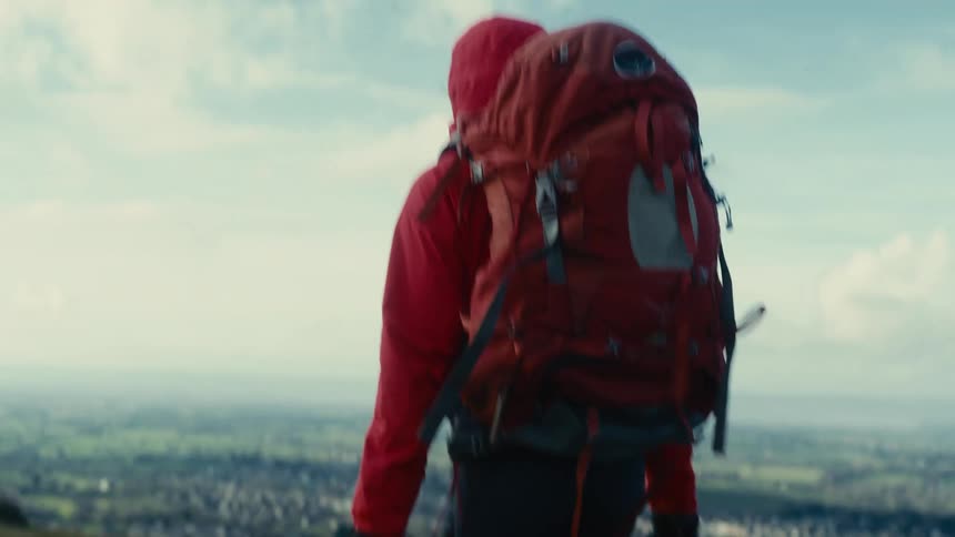 Person wearing a red hood and carrying a backpack hiking outdoors during day time