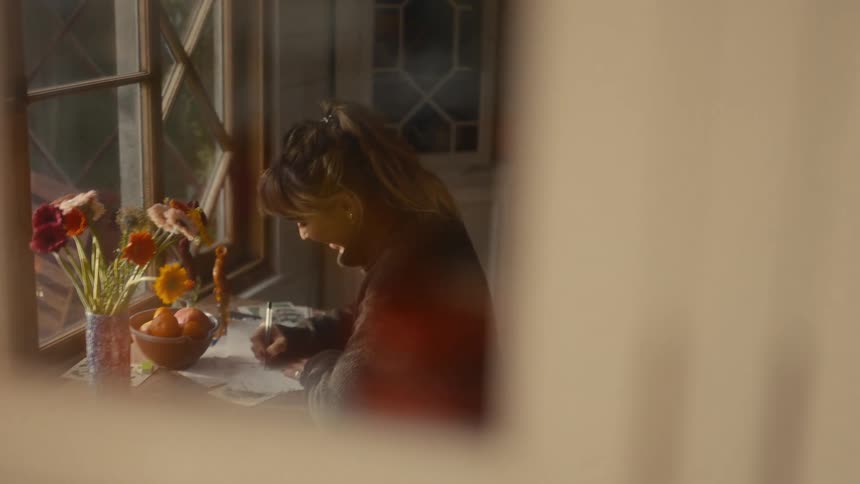 Mirror reflects a woman sitting and writing during the daytime