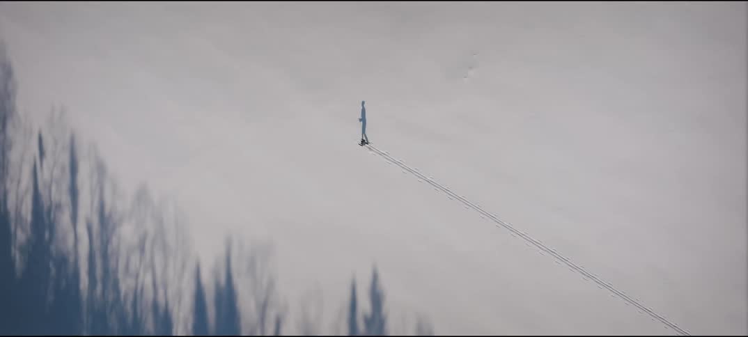 Skier walks up the snowy slope on a winter day leaving ski tracks