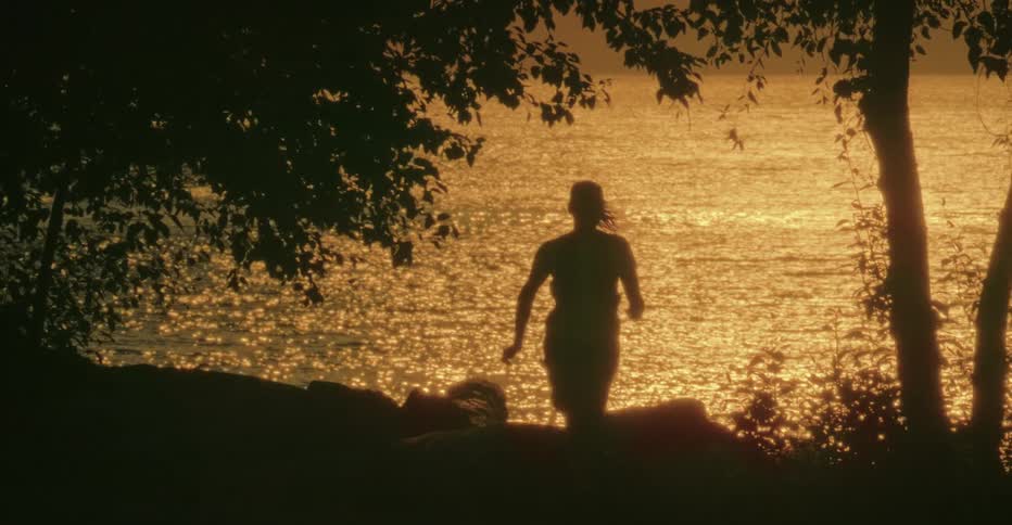 A woman running near a lake at sunset