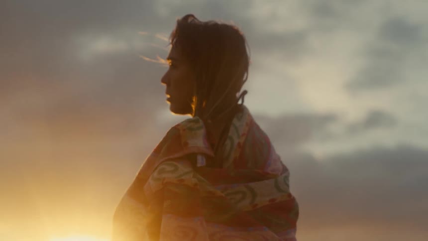 Young woman standing on the beach as she uses a towel to dry her hair
