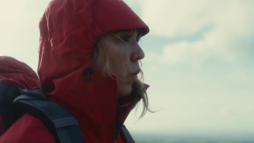 A woman in a jacket outdoors on a sunny day