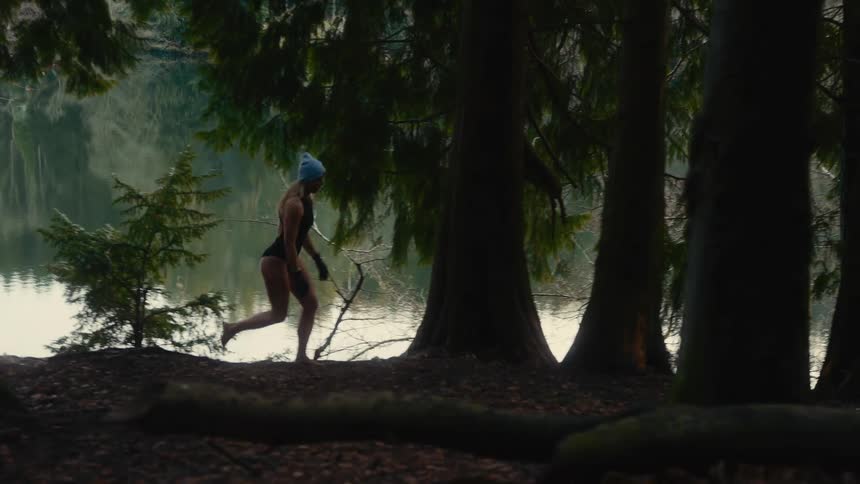 Woman walking through the woods by a lake