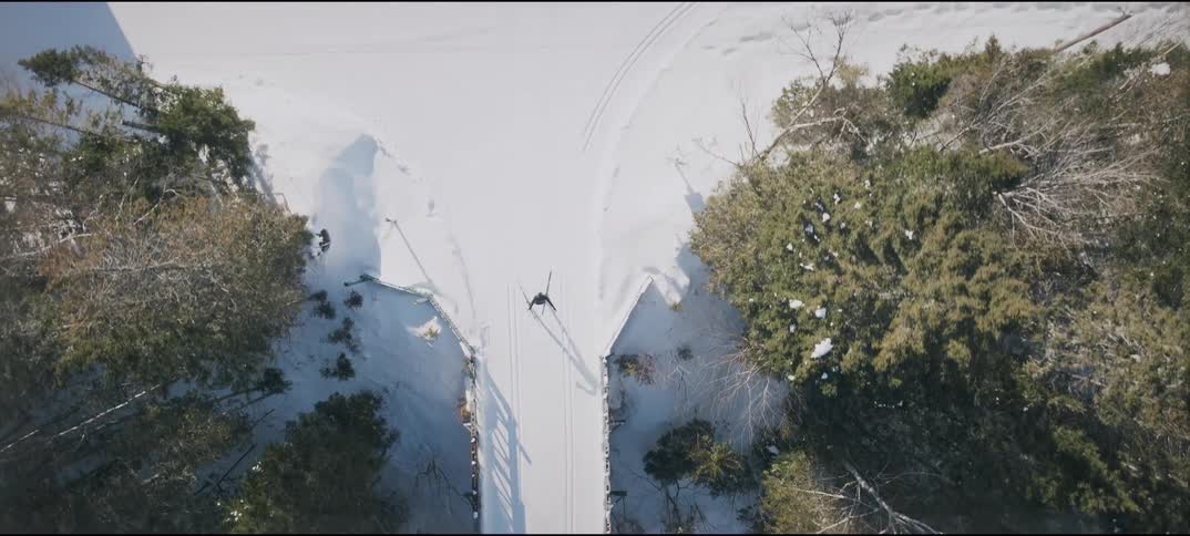 Aerial view of a skier crossing a bridge over a stream