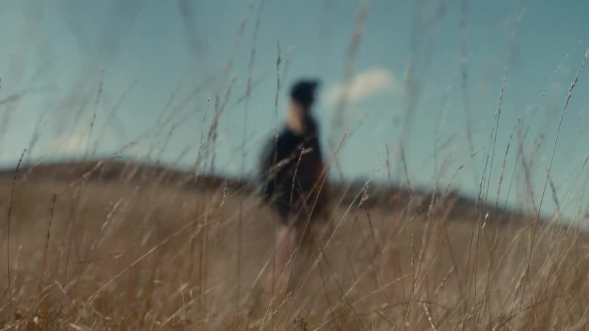 The woman standining the grass on a windy day