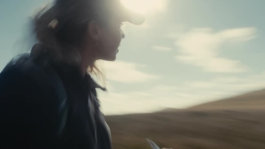 A woman wearing a cap in an outdoor desert setting on a clear day with blue clouds in the sky