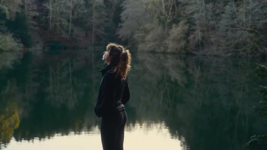 Woman stands on the coast overlooking a river in the forest