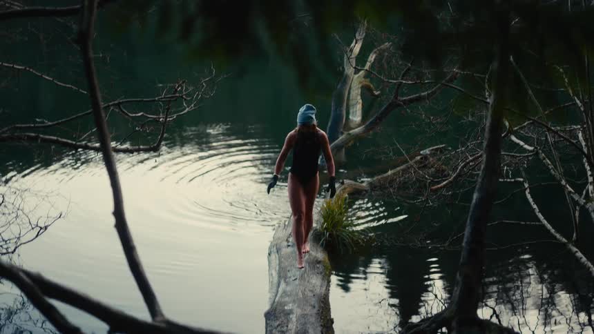 The woman balances over the log on the lake