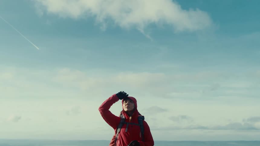 The woman looks up at the sky as she hikes