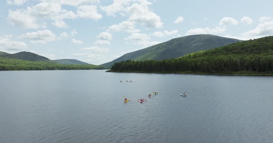 Kayaks moving across a lake surrounded by mountains