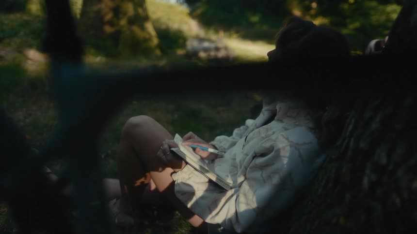 A woman sitting outdoors writing in a book