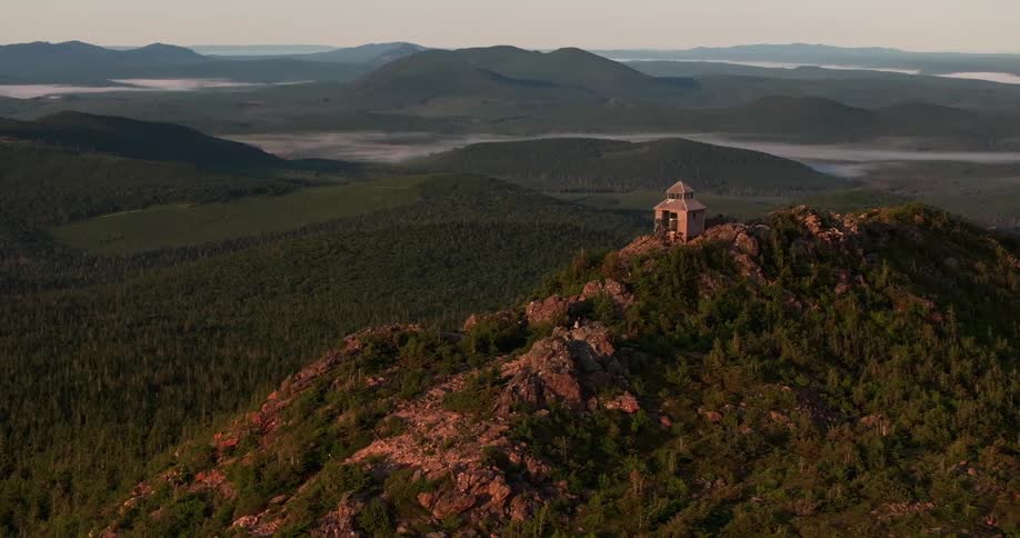 Isolated cabin on a mountaintop surrounded by forests