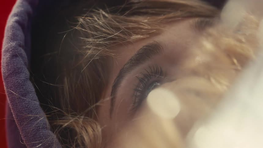 The partially covered face of a woman blinking in sunlight outdoors