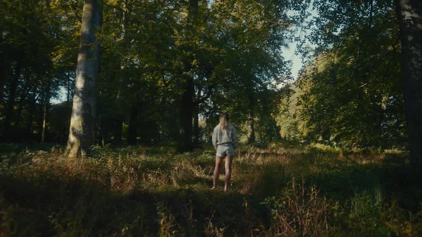 Female person wearing a hat standing outdoors surrounded by trees