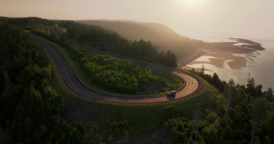 Aerial of a vehicle driven on a curved highway in a rural area during daytime