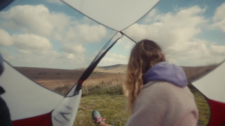 Woman sitting inside a tent looking at the open landscape