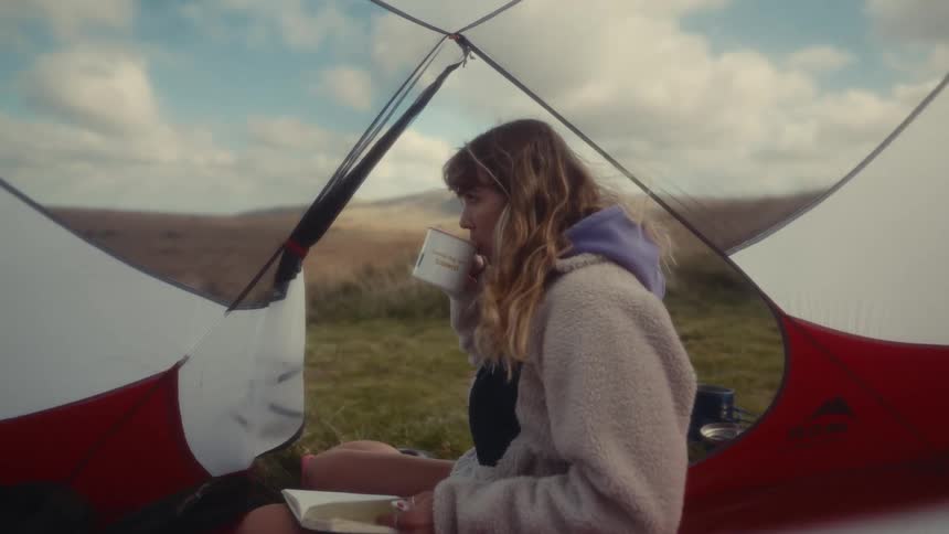 Woman sitting in the tent drinking a hot beverage