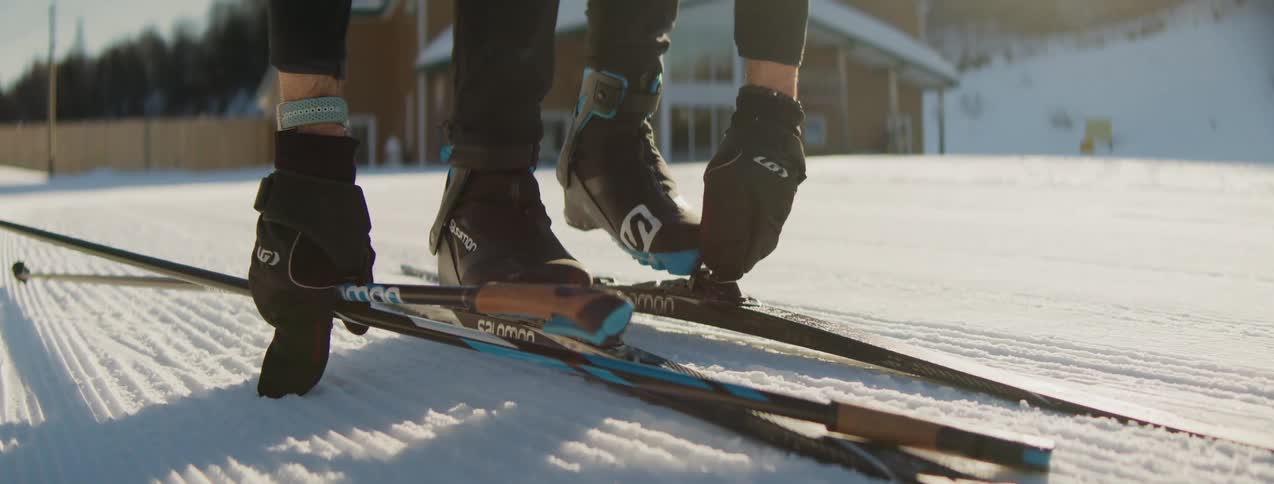 A man is strapping two skis to his feet while in a completely different environment