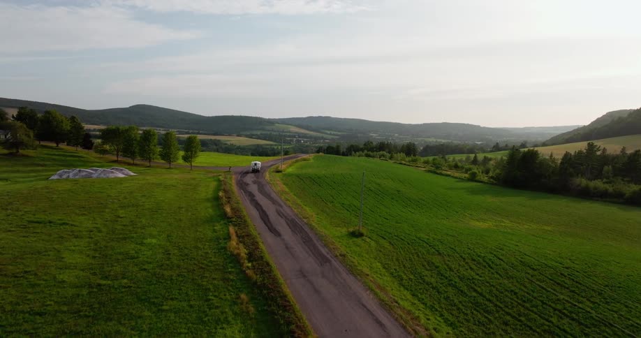 Truck traveling on a rural road surrounded by green fields