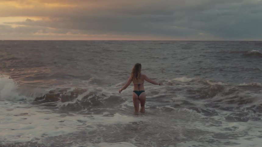 Woman walking into the sea during dusk