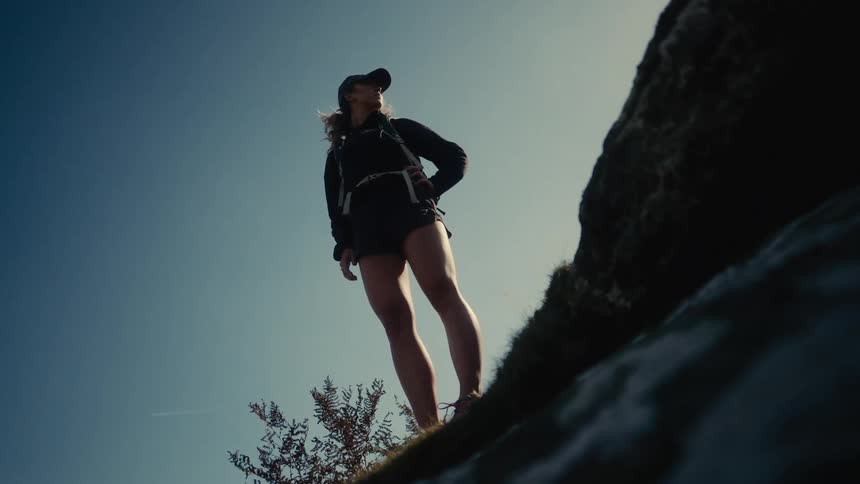 Young woman standing at the edge of a mountain looking around