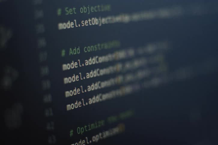 Lines of programming code scroll vertically on a dark computer screen