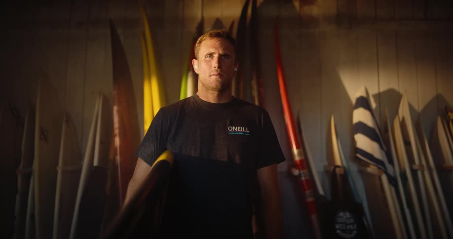 Man standing among surfboards lined up against the wall