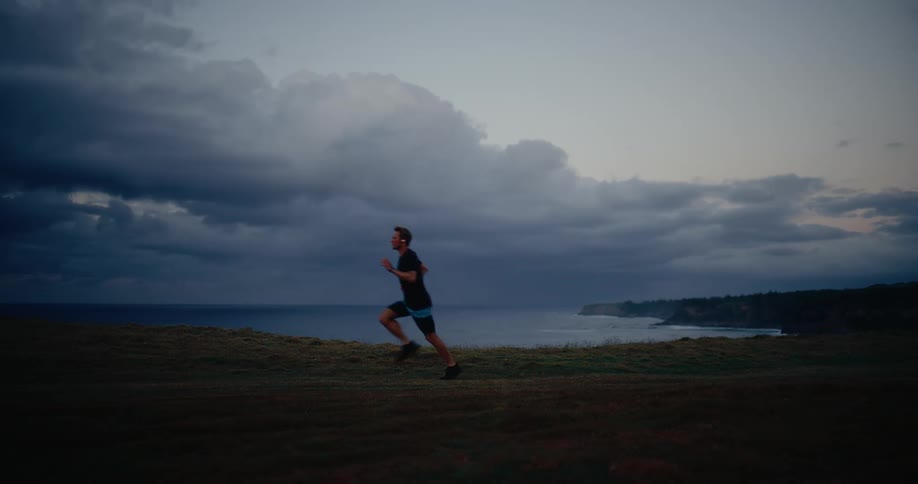 Man running on coastal terrain at dusk