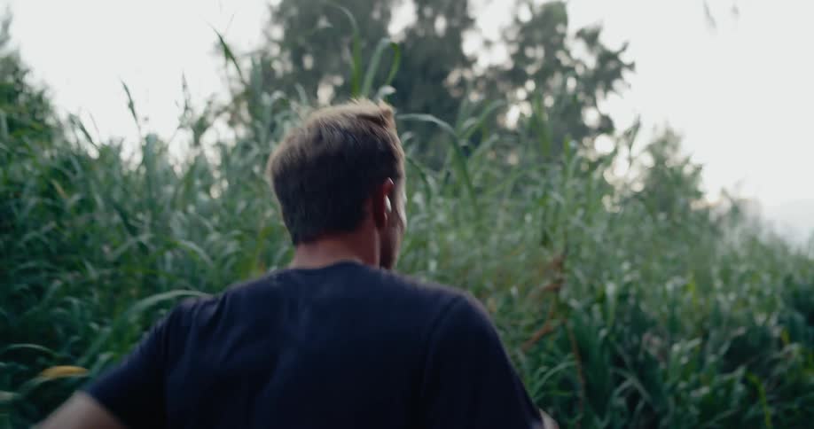 Close up of a middle aged man jogging outdoors on a road besides a grass field during daytime