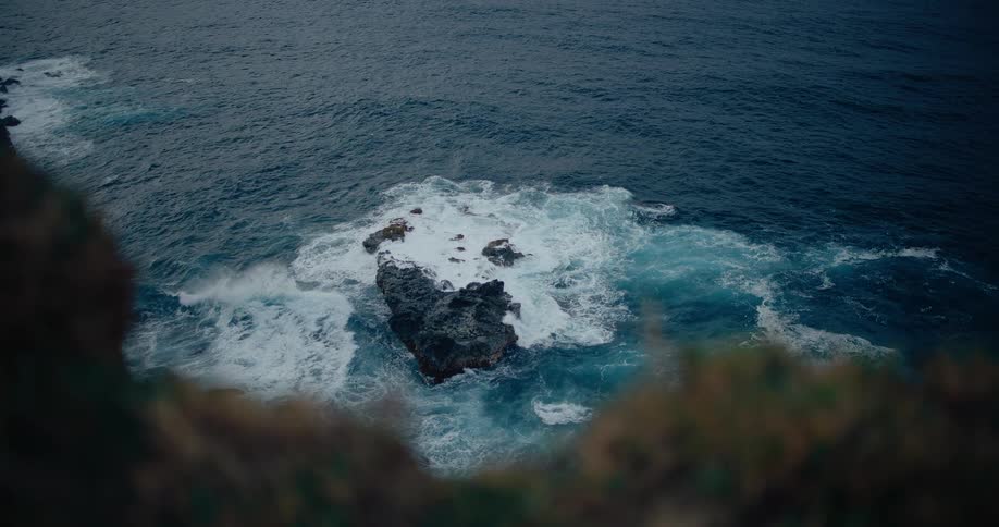 Ocean waves flowing against a coastal rock formation in daytime