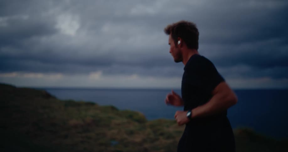 Man running in a coastal area under a cloudy sky