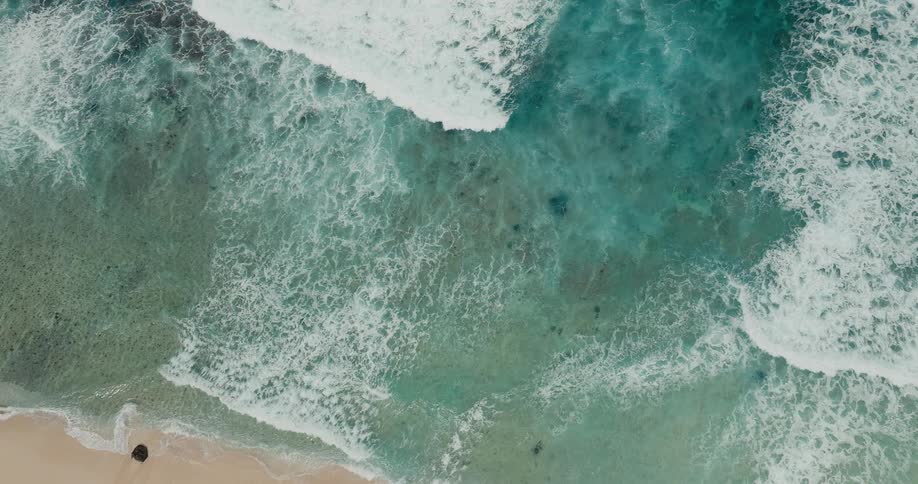 Waves gently hitting the sandy shoreline at midday