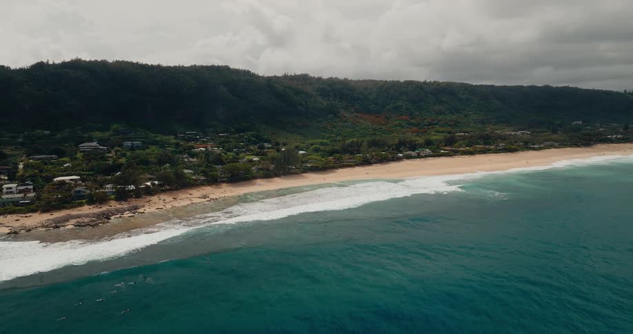 A coastline with a coastal town along the shore as light waves hit at midday
