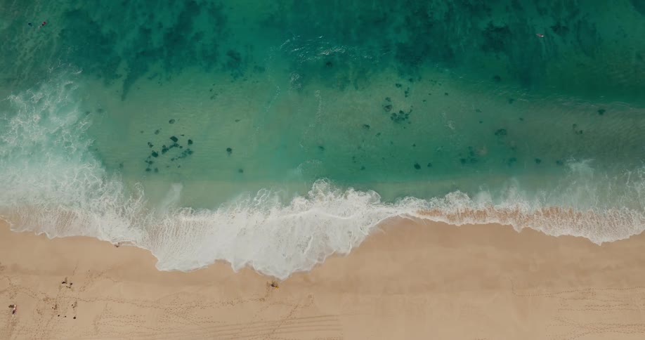 A beach with sand struck by sea waves at midday