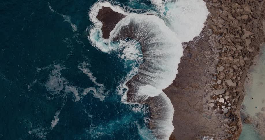 Strong waves breaking against the rocky coastline seen from above