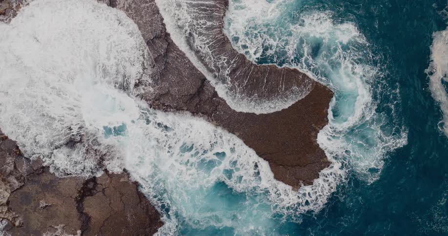 Waves crashing over coastal rocks seen from above