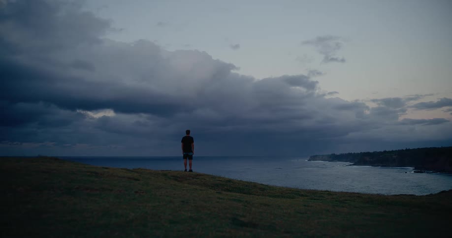 The man is watching the sunrise on the shore