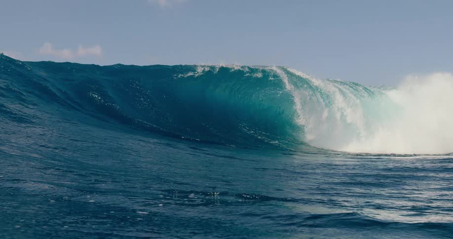 Massive deep blue wave curls and crashes with white foam in the open ocean as the viewpoint becomes submerged in the water