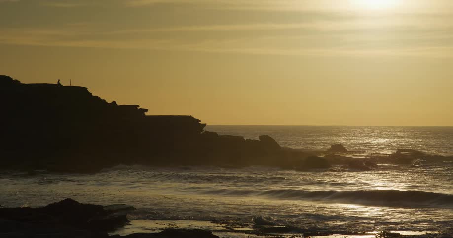 People walking along the sea coast outdoors at sunset
